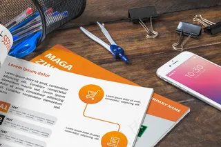 杂志和智能手机模型样机放在木桌上，上面有钢笔和尺子