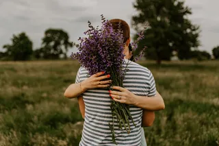 一个黑发男人穿着条纹t恤站在后面拥抱一个女人。
