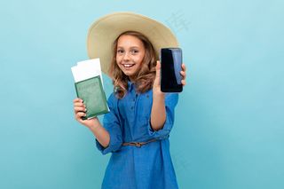 迷人的女孩出示护照，带着机票，电话，欣喜若狂