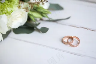 木桌上摆着白玫瑰的结婚戒指