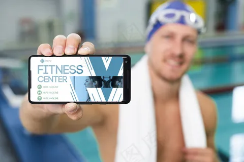 游泳运动员手持一部带有健身中心登陆页面的手机