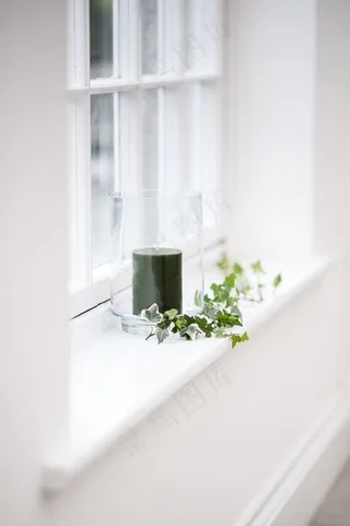 一支黑色蜡烛在窗台上用树叶装饰的玻璃中的美丽垂直镜头