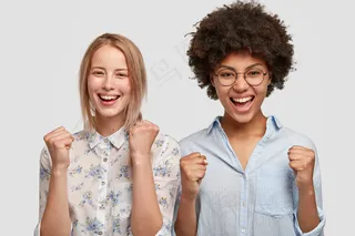 快乐混血女的横拍快乐地握拳，对比赛结果感到满意，为自己喜欢的球队呐喊，有快乐的表情，孤立在白墙上