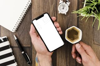 平躺的手拿着智能手机模型样机和咖啡