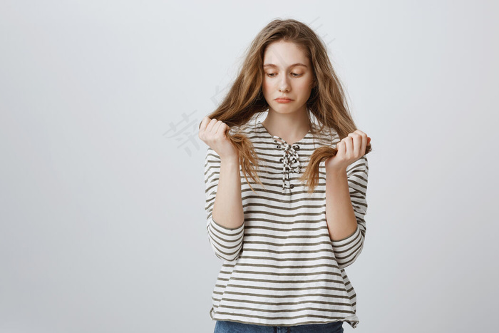 忧郁的女孩看着自己的头发，需要新发型