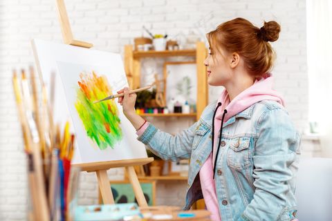 年轻漂亮的女画家在画架上画抽象画