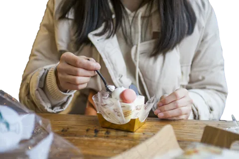 一个穿棉服的女孩在吃蛋糕