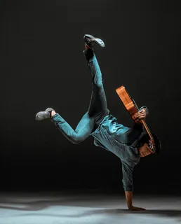 很酷的家伙拿着吉他站在黑暗的背景上