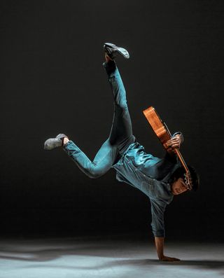 很酷的家伙拿着吉他站在黑暗的背景上