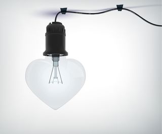 现实的电灯泡情色概念在心形与电源线在灰色隔离