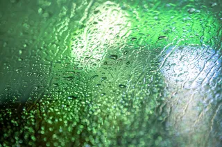 抽象的彩色背景玻璃表面与水滴和模糊的城市灯光。