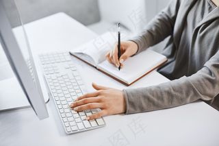 我可以处理多种任务。成功的女孩一边看电脑屏幕一边学习新的商业图形一边用键盘打字和做笔记。没有时间休息了