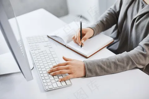 我可以处理多种任务。成功的女孩一边看电脑屏幕一边学习新的商业图形一边用键盘打字和做笔记。没有时间休息了 我可以处理多种任务。成功的女孩一边看电脑屏幕一边学习新的商业图形一边用键盘打字和做笔记。没有时间休息了
