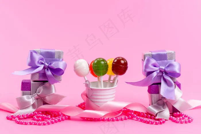 一个前视图棒棒糖和盒子紫色礼品盒孤立的粉红色，生日庆祝派对