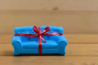 蓝色沙发，木质背景上系着红色的礼品带。不寻常的礼物。
