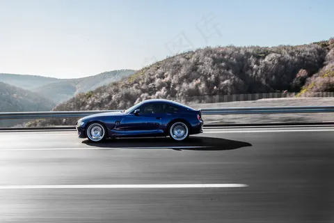 一辆海军蓝轿跑车在阿克罗斯山脉的高速公路上行驶。
