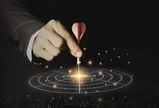 执行营销手拿着红色飞镖放在目标板的中心。企业投资目标和目标概念。