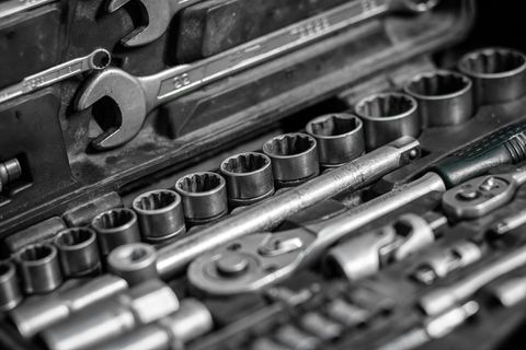 平放金属工具：扳手、棘轮、一套不同尺寸的可互换头等工具都在工具箱内，顶视图。