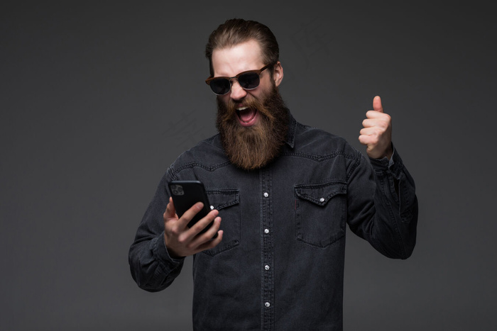 兴奋开朗的男子穿着衬衫用手机庆祝与世隔绝