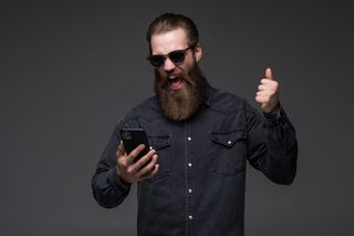 兴奋开朗的男子穿着衬衫用手机庆祝与世隔绝