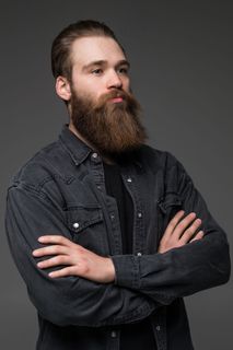 迷人的长胡子男人双手交叉在孤立的灰色背景上