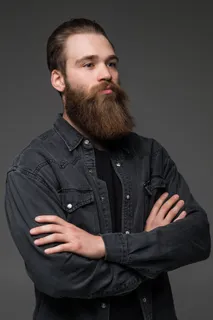 迷人的长胡子男人双手交叉在孤立的灰色背景上