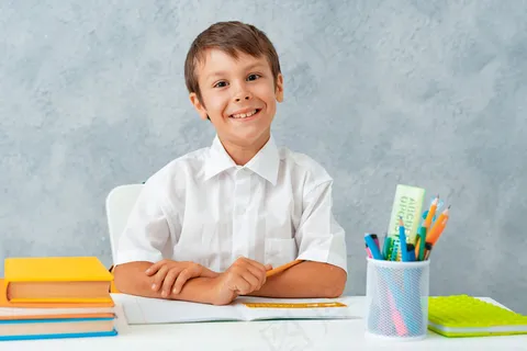 回到学校。快乐微笑的学生在书桌前画画。