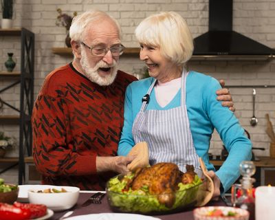一对老夫妻在厨房里玩,手里拿着火鸡 一对老夫妻在厨房里玩,手里拿着火鸡