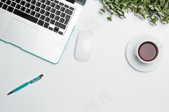 办公桌上有电脑、用品、鲜花和咖啡杯。