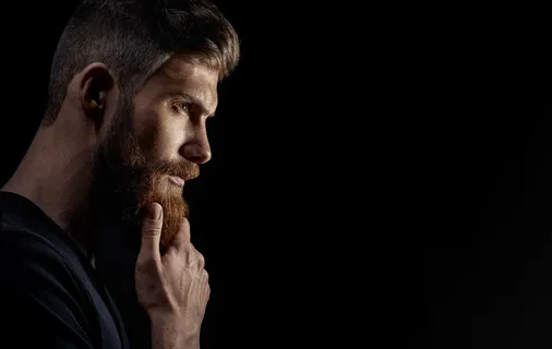 迷人的、沉思的、留着胡须的年轻人望着远处