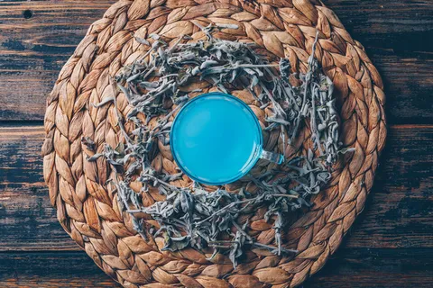 茶壶中的蓝色水，深色木质背景上有茶水俯视图