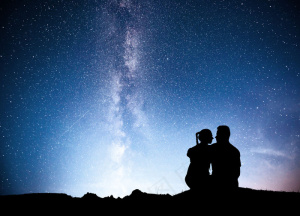 站在星光下的山上的男人和女人。在紫色的银河系中拥抱情侣。