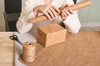 重点放在女人手上的白色针织毛衣包装盒里。手工包装纸和天然绳线。节日礼物，惊喜。节礼日礼物