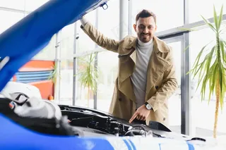 一名男子在汽车经销店检查一辆新车的引擎盖下