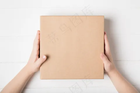 儿童手中的方形纸盒。顶视图，白色背景