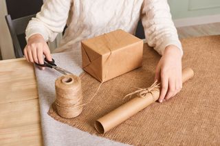 重点关注女士手上白色针织毛衣包装箱。手工包装纸和天然绳线。节日礼物快乐，惊喜。礼礼日礼物