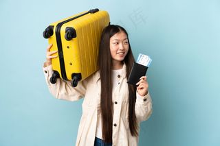 带着旅行箱和护照的年轻中国女孩*度假