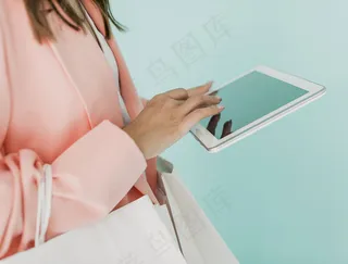 黑发女人拿着平板电脑和购物袋