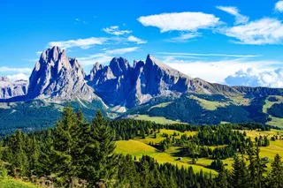 蓝天下的巍峨山脉与翠绿原野