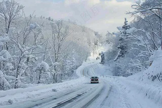 冬天雪山山区公路行驶的汽车白雪覆盖寒冷摄影图