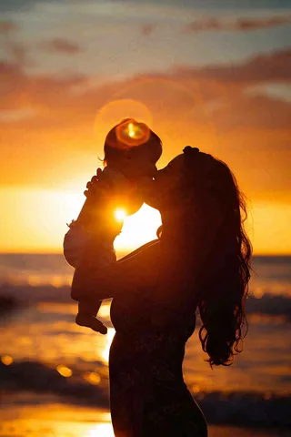 母亲节晚霞妈妈抱孩子温馨摄影图