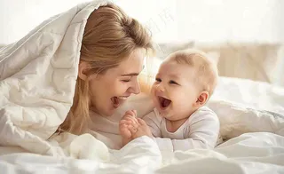 妈妈陪着婴儿玩耍白色床温馨母亲节摄影图