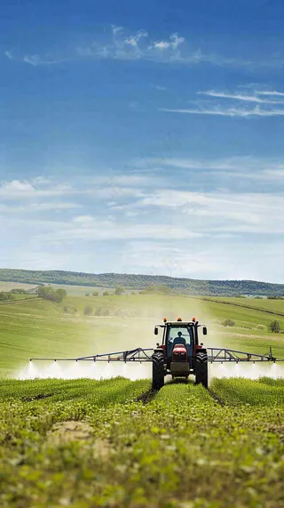 农田庄稼里耕种的机器农忙劳动节摄影图