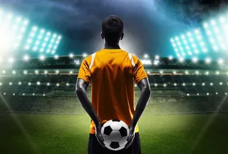 拿着足球站在足球场上的运动员高清图片