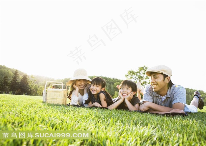 趴在户外草坪上玩乐的父母孩子