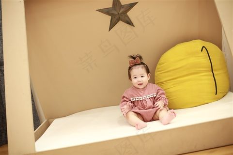 坐在小床上开口笑的可爱小女孩