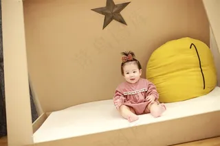 坐在小床上开口笑的可爱小女孩