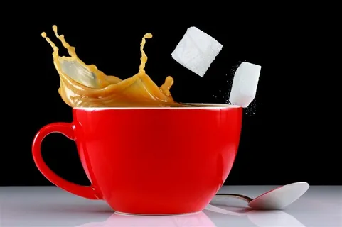 红色咖啡杯里喷溅的咖啡和白色方糖高清图片