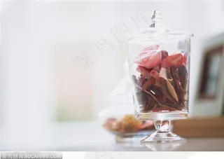 桌子上摆放的玻璃瓶里的干花瓣