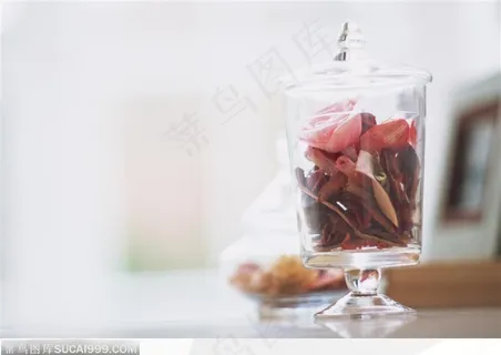 桌子上摆放的玻璃瓶里的干花瓣 桌子上摆放的玻璃瓶里的干花瓣